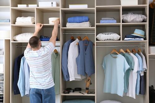 Man Reaching For Box On Wardrobe Shelf